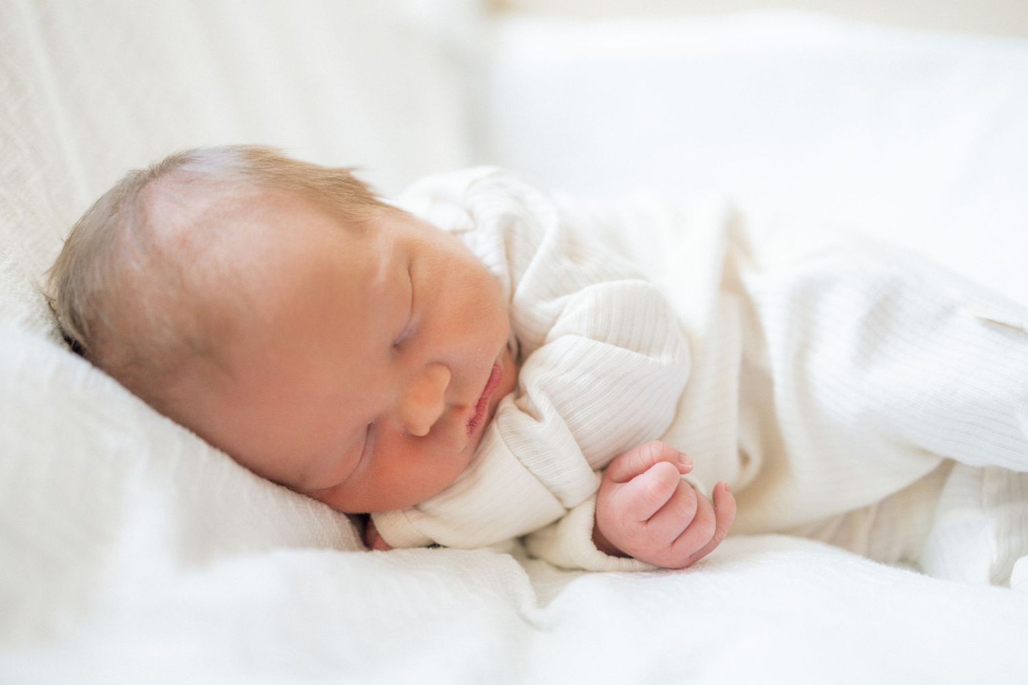 Peaceful newborn baby sleeping in white blanket wearing white outfit at University of Tennessee Medical Center.