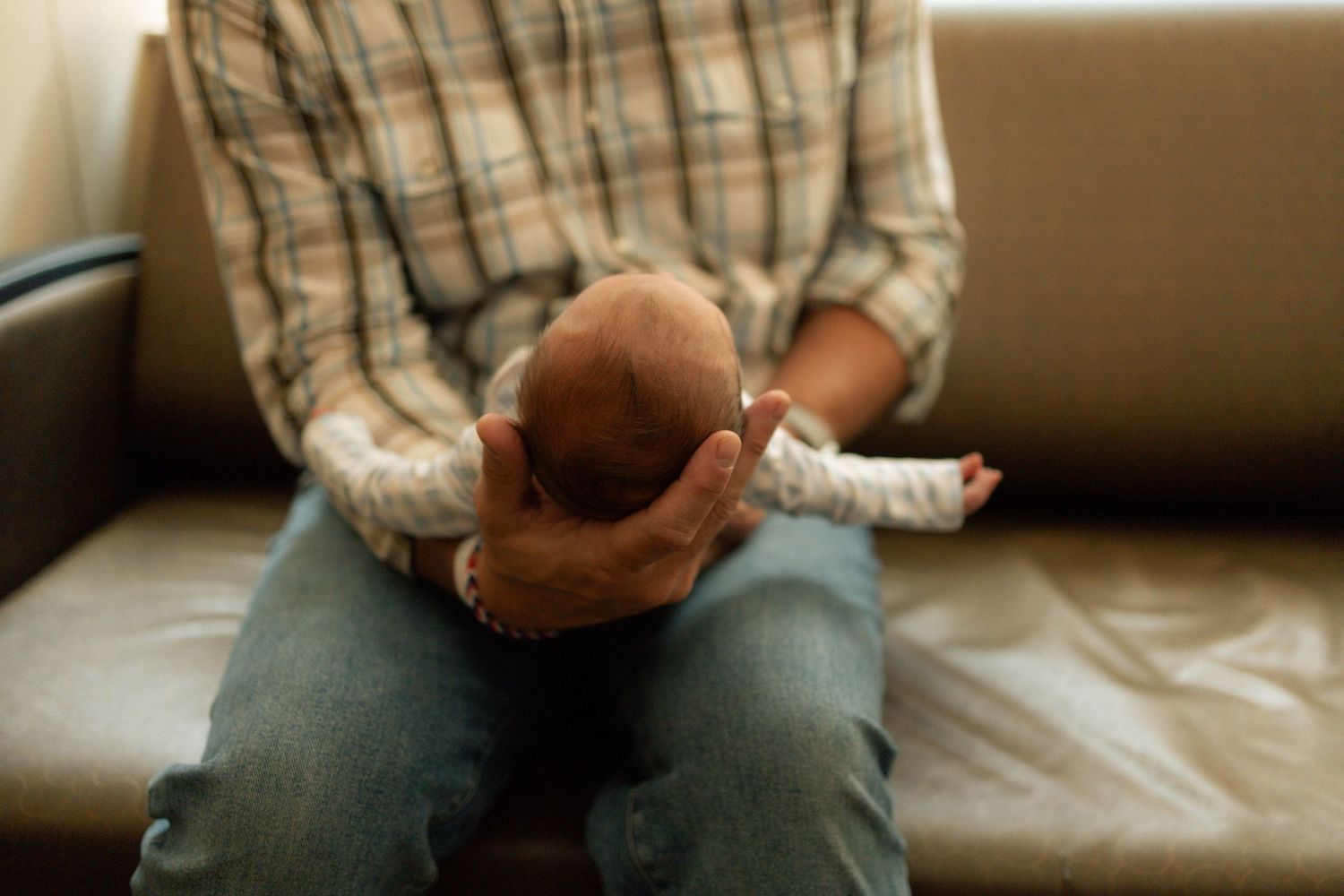 Adult cradling a newborn baby on a couch in a tender parenting moment at University of Tennessee Medical Center.