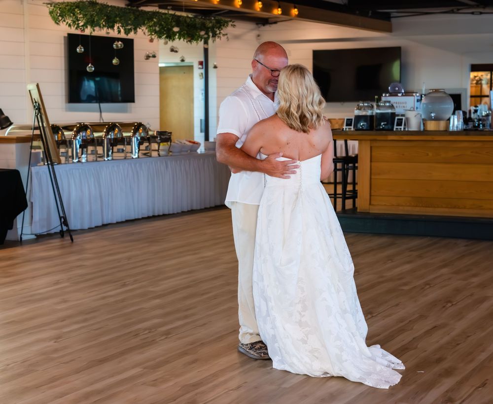 Bride and groom sharing their first dance at a wedding reception on a hardwood dance floor.