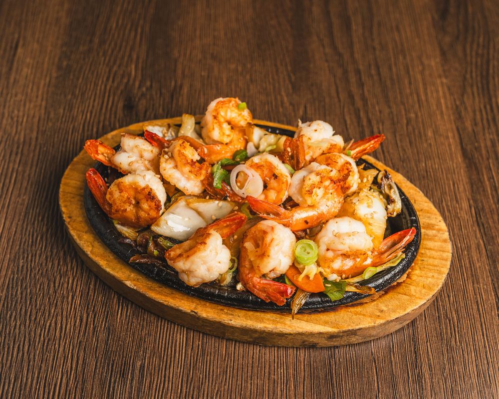 Sizzling shrimp fajitas served on a cast iron skillet with vegetables on a wooden board.