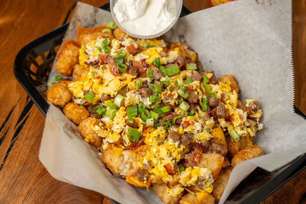 Loaded tater tots topped with scrambled eggs, bacon, green onions, and cheese, served with sour cream dipping sauce.