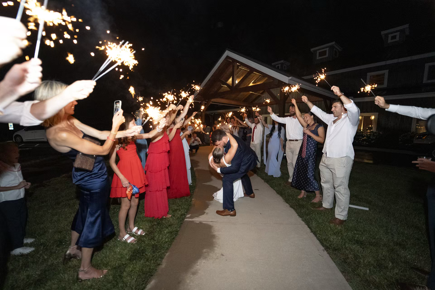 Guests line a pathway holding sparklers at an outdoor wedding sendoff ceremony at Stone Valley Meadows venue