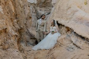Bride and groom pose romantically in a rocky canyon wearing wedding attire.