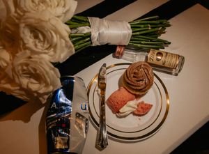 White rose bridal bouquet beside dessert plate and accessories on white table at wedding reception.