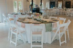 Elegant wedding reception table with white linens, gold chargers, and pastel floral centerpieces.