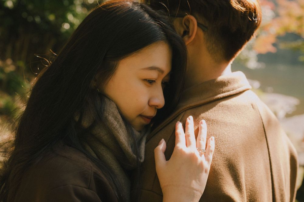 Couple sharing a tender embrace outdoors with warm autumn colors in the background.
