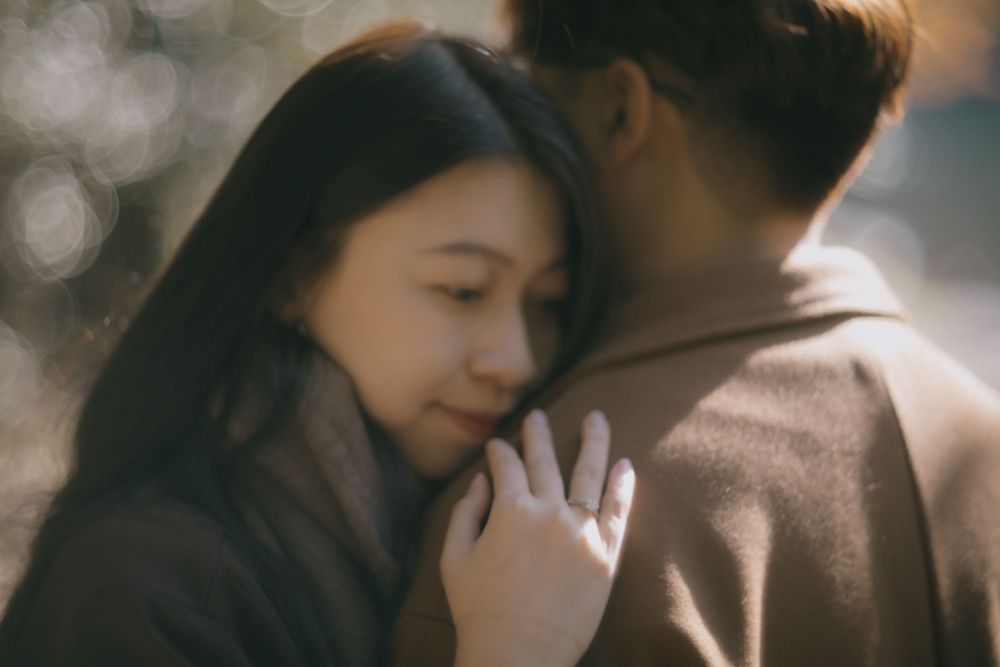 Young woman resting her head on a mans chest in a soft bokeh romantic close-up.