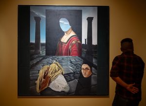 A man views a surrealist painting featuring a figure with a sky-filled face amid ruins in a gallery.