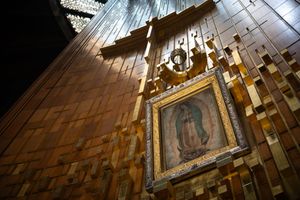 Golden ornate frame displaying the Virgin of Guadalupe image on a decorative wooden tile wall in a Mexican basilica.