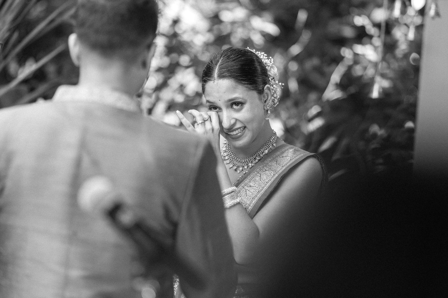 Black and white wedding reception photo of couple sharing first dance surrounded by guests in elegant venue.