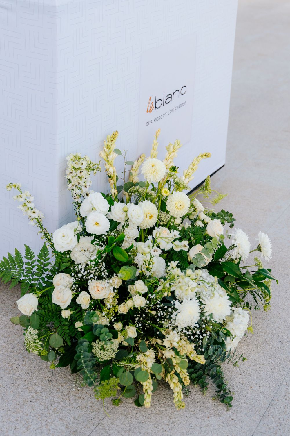 Elegant white floral arrangement with roses and greenery displayed in front of a Le Blanc spa resort logo box.