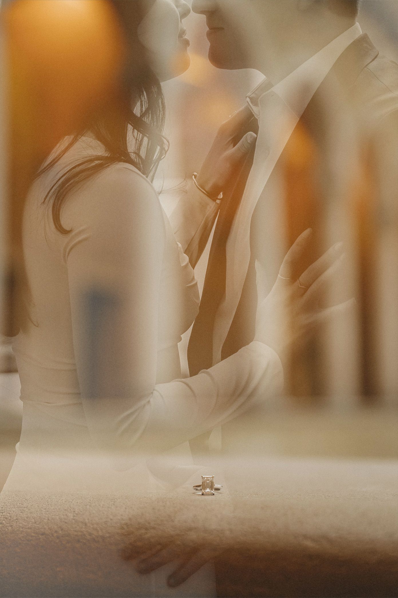 Romantic double exposure photo of a couple embracing with an engagement ring in the foreground.