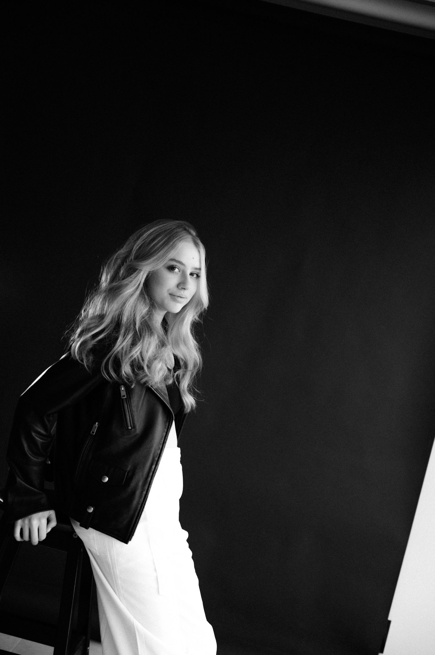 A dynamic black and white portrait series showing candid smiling poses in a dark studio setting against a light background.