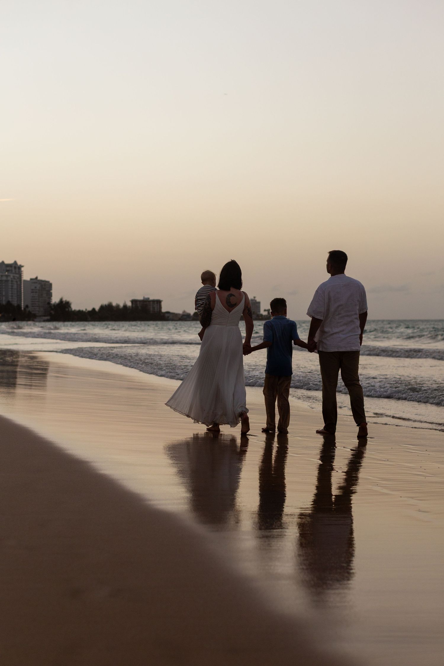 Family portrait on the beach in Isla Verde, Carolina, Puerto Rico. Father, mother and two sons. Sunset silhouette.