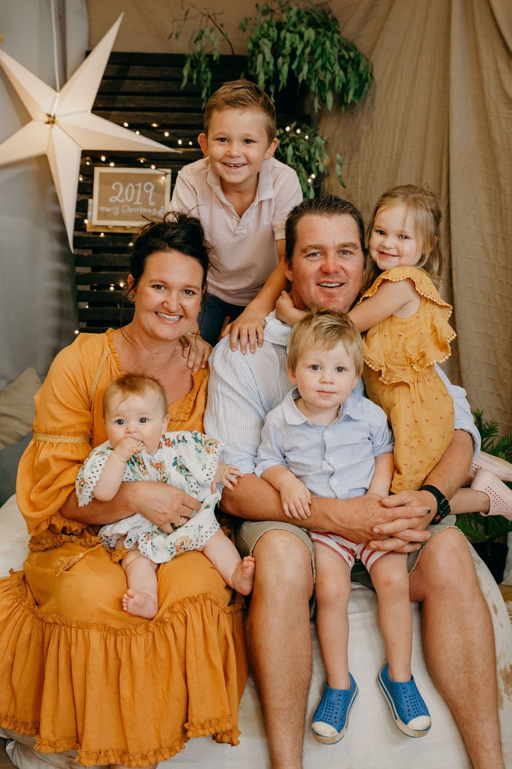 Smiling family of six with four kids posing in a festive boho-styled Christmas portrait session.