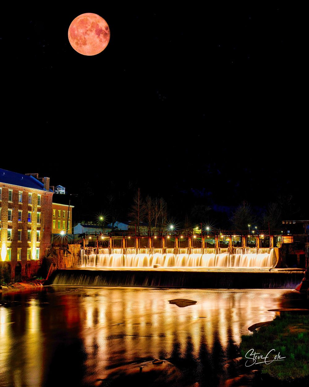 Full supermoon shining over illuminated Prattville Dam spillway and mill reflecting in the river, photo by Steve Cole Photography.