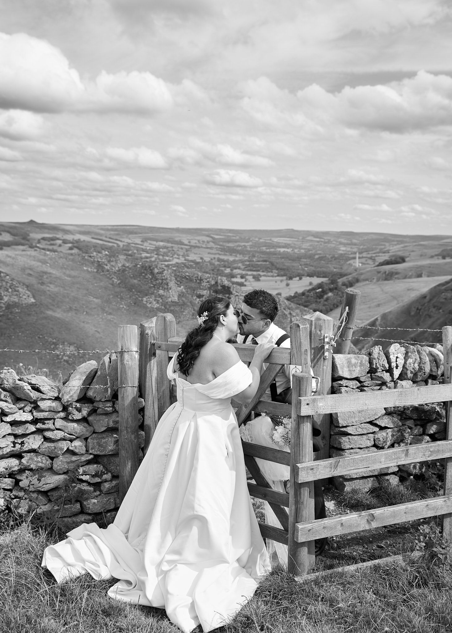 Bride and groom gazing at each other in a sunlit field with a scenic countryside estate backdrop.