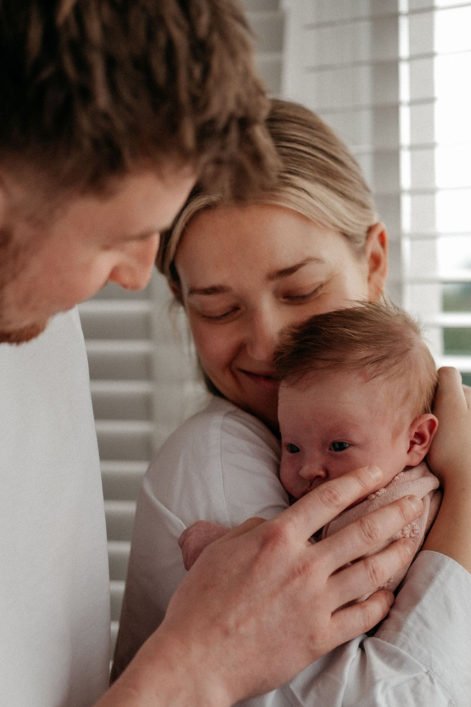 Mom and dad hold newbron baby at home portrait session in Gosforth