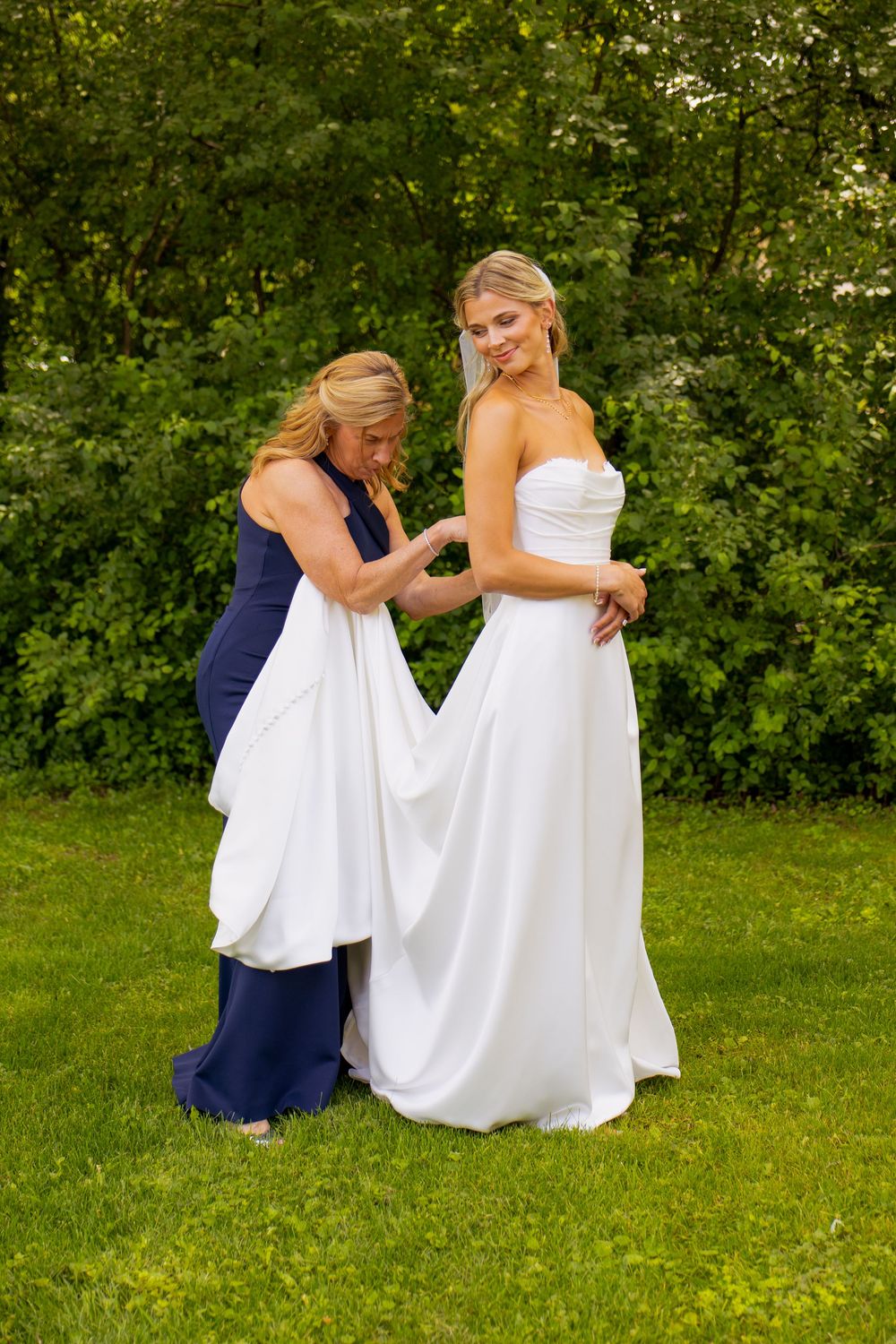 A bride's mother helps her button her dress