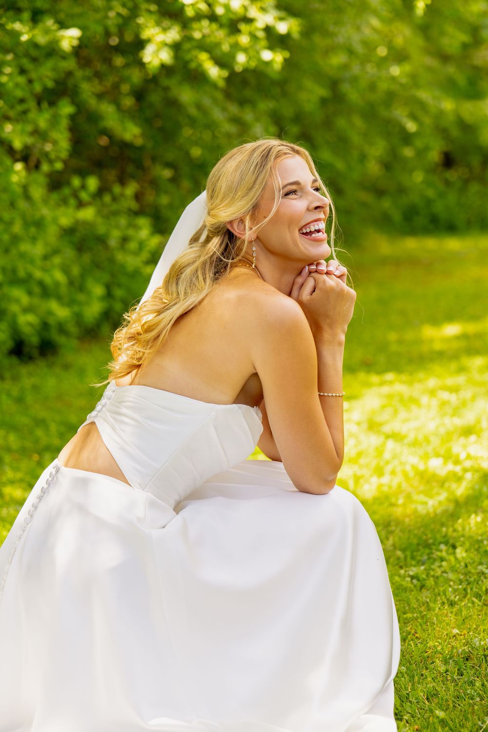 A woman in a wedding dress smiling outdoors