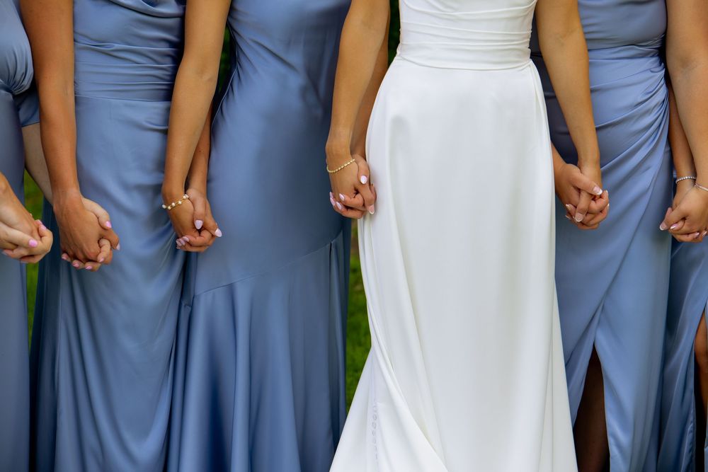 A bride holds hands with her bridesmaids
