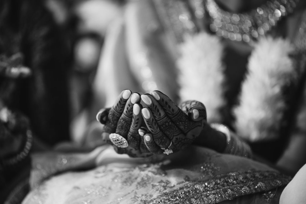 Close-up black and white photo of hands adorned with henna during a traditional Indian wedding ceremony.