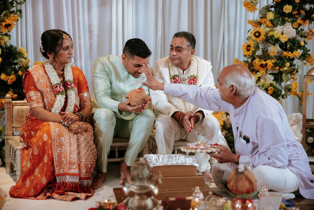 Traditional Indian wedding ceremony with family members in colorful attire performing rituals with a priest.