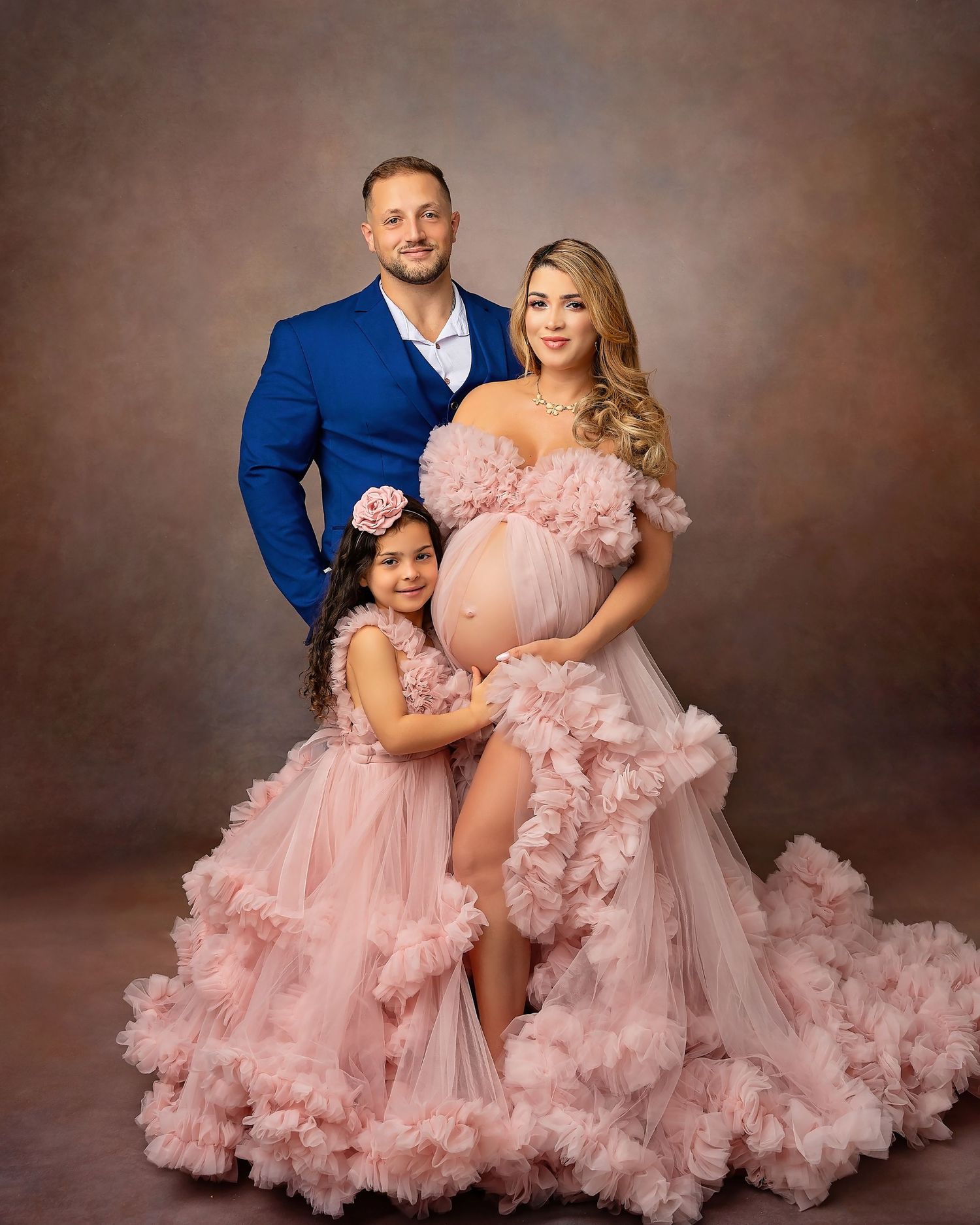 Mother and daughter sharing a tender moment during a maternity family portrait session featuring coordinated dresses and elegant styling