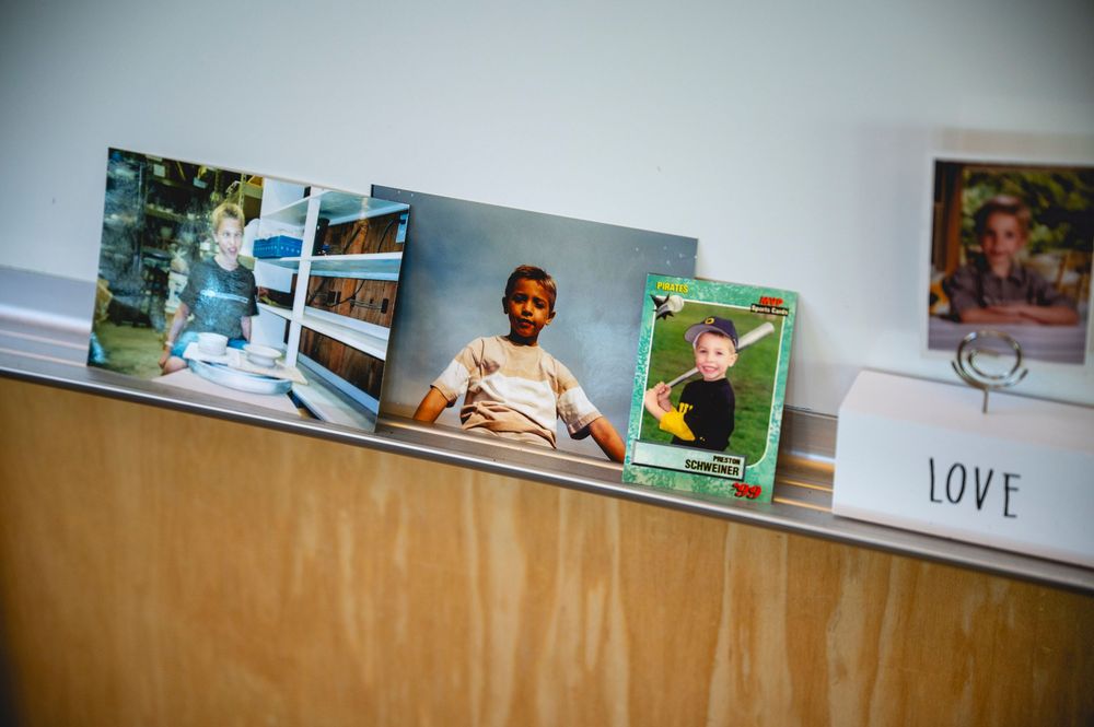 Photos of children displayed on a shelf next to a white box labeled LOVE in a bright, modern room.