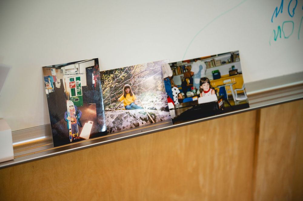 Three framed photos displayed on a shelf ledge in a classroom setting, featuring colorful personal photographs.