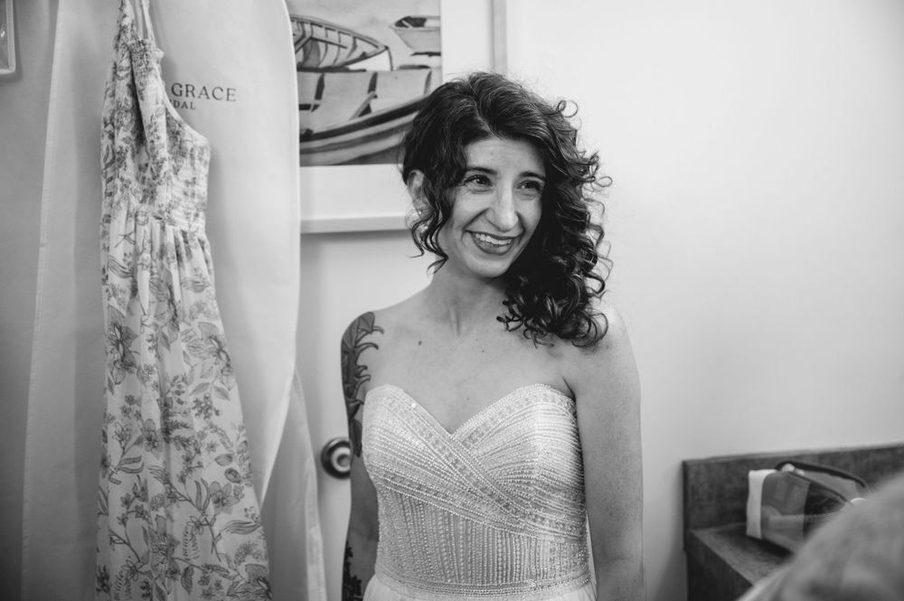 Smiling tattooed bride in strapless beaded wedding gown, black and white photo.