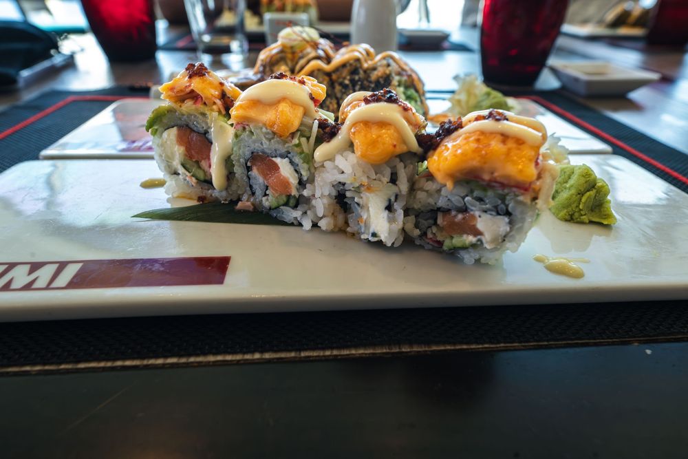 Delicious sushi rolls topped with creamy sauce and shrimp served on a white plate at a Japanese restaurant.