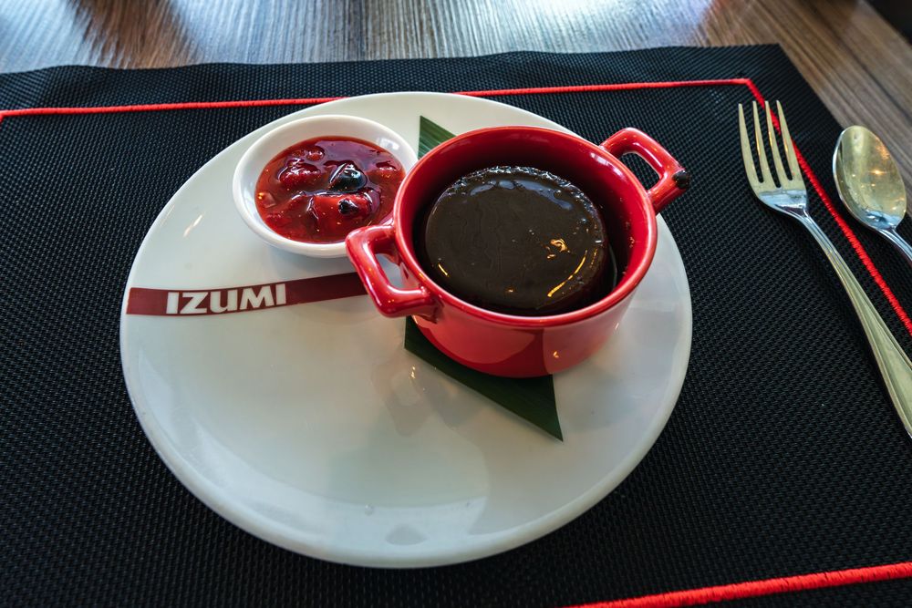 Red cocotte with chocolate lava cake and berry sauce on white plate at Izumi restaurant.