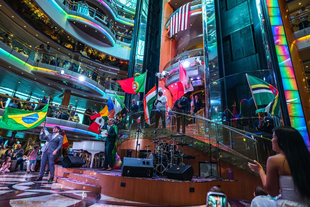 International flags displayed in a grand cruise ship atrium during a multicultural celebration event.