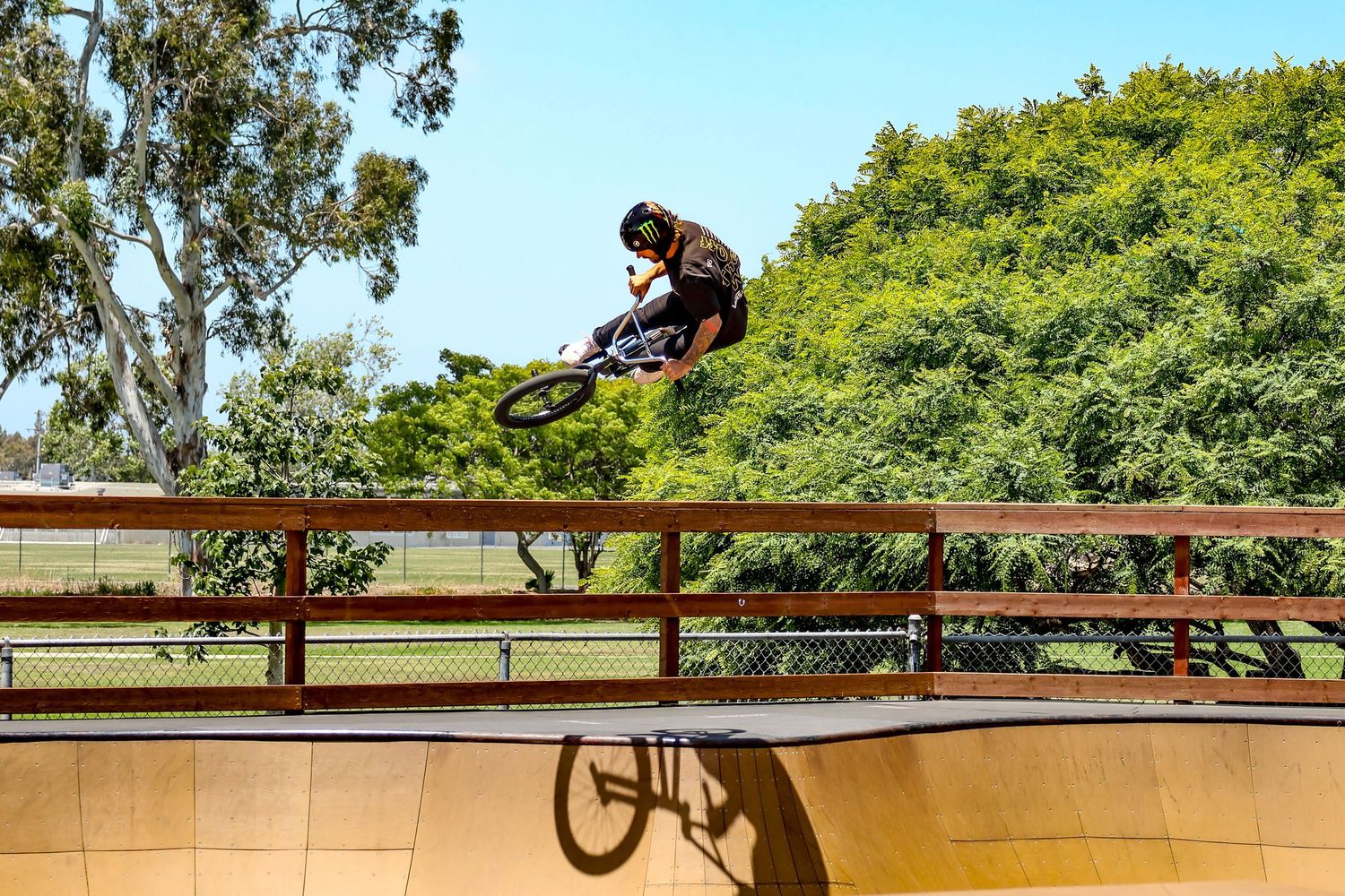 San Diego action sports photography of a BMX rider catching big air over a wooden skatepark ramp.