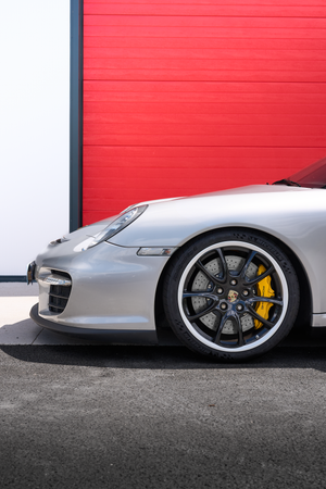 Silver Porsche 911 GT2 front wheel with yellow calipers against red garage door.