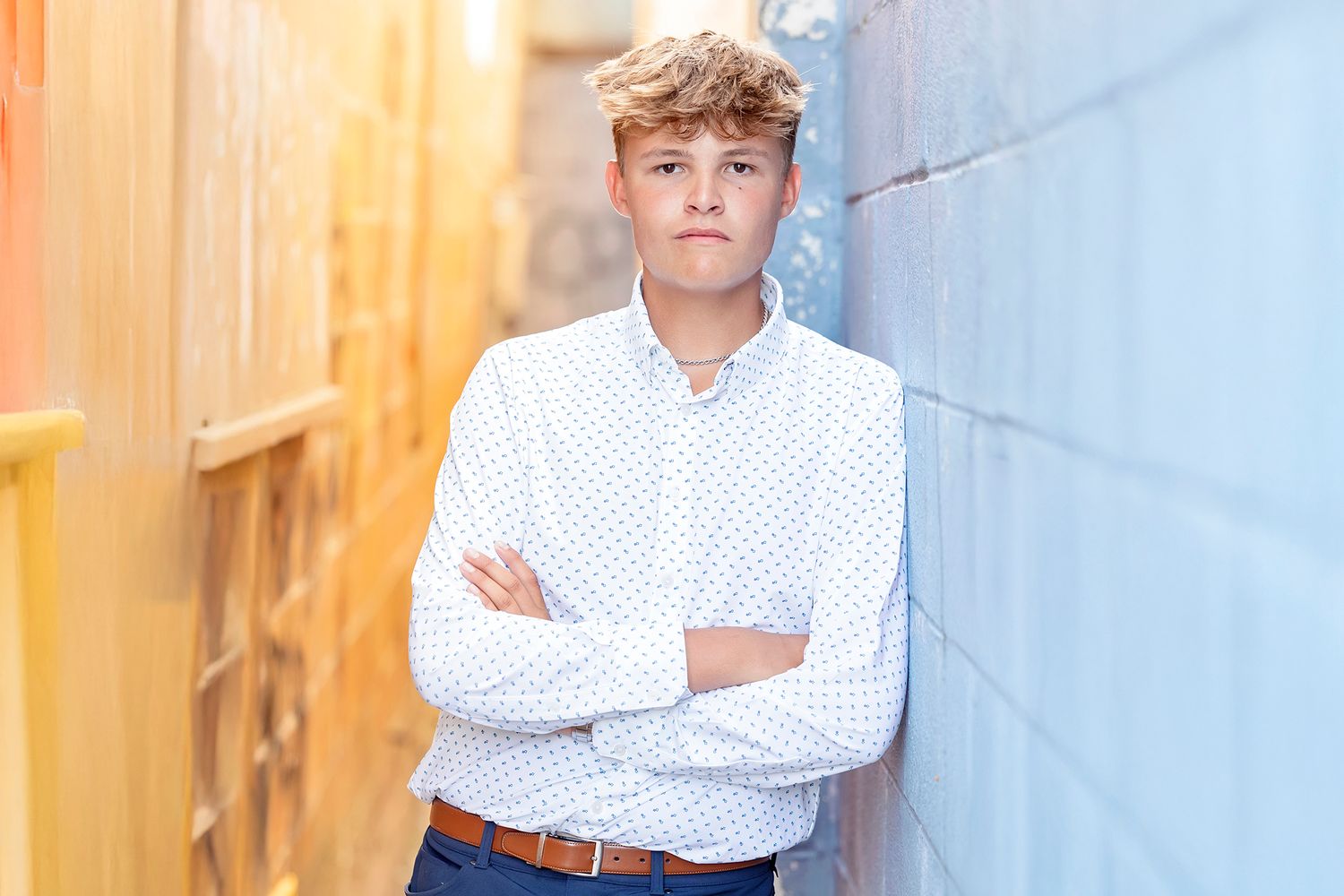 High school senior boy posing by colorful buildings during a senior photography session in Clear Lake, Iowa.