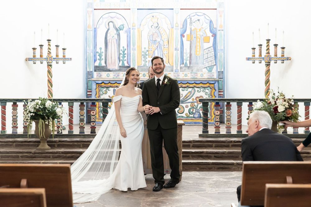 Bride and groom smiling at the altar of a decorated church during their wedding ceremony.