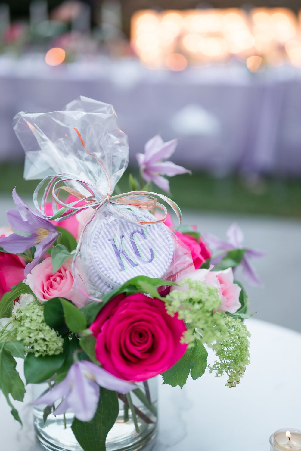 Floral centerpiece with pink roses and monogrammed KC tag in glass vase.