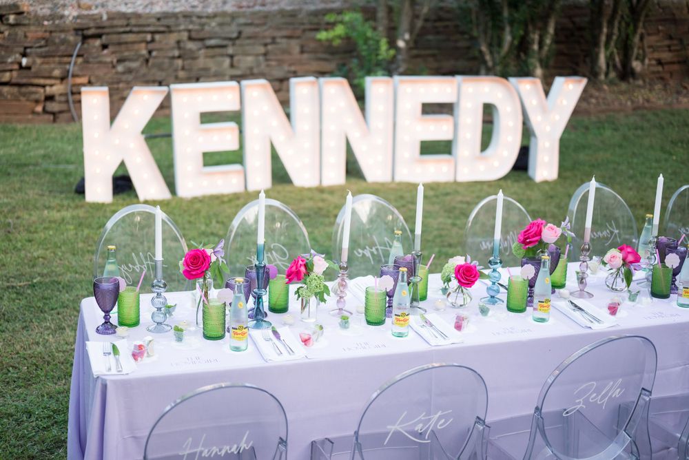 Elegant party table setting with Kennedy name sign and clear acrylic chairs.