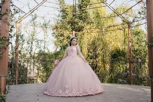 Pink quinceañera dress showcased under an outdoor gazebo with decorative columns.