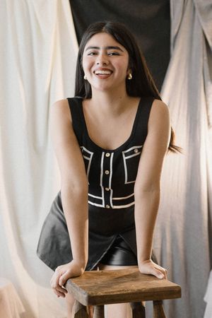 A casual portrait session with black top against white curtain backdrop.