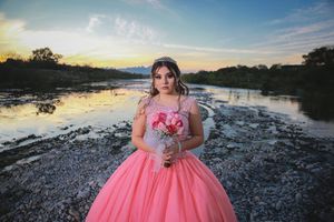 Pink formal dress photographed at sunset by a rocky riverbank.