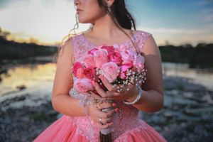 Close-up of pink floral bouquet held against a pink tulle ballgown.