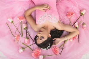 Dreamy pink tulle dress photoshoot with scattered roses and soft lighting.