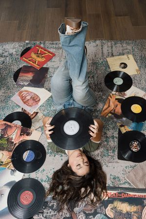 Collection of vinyl records arranged on a wooden floor in artistic layouts.