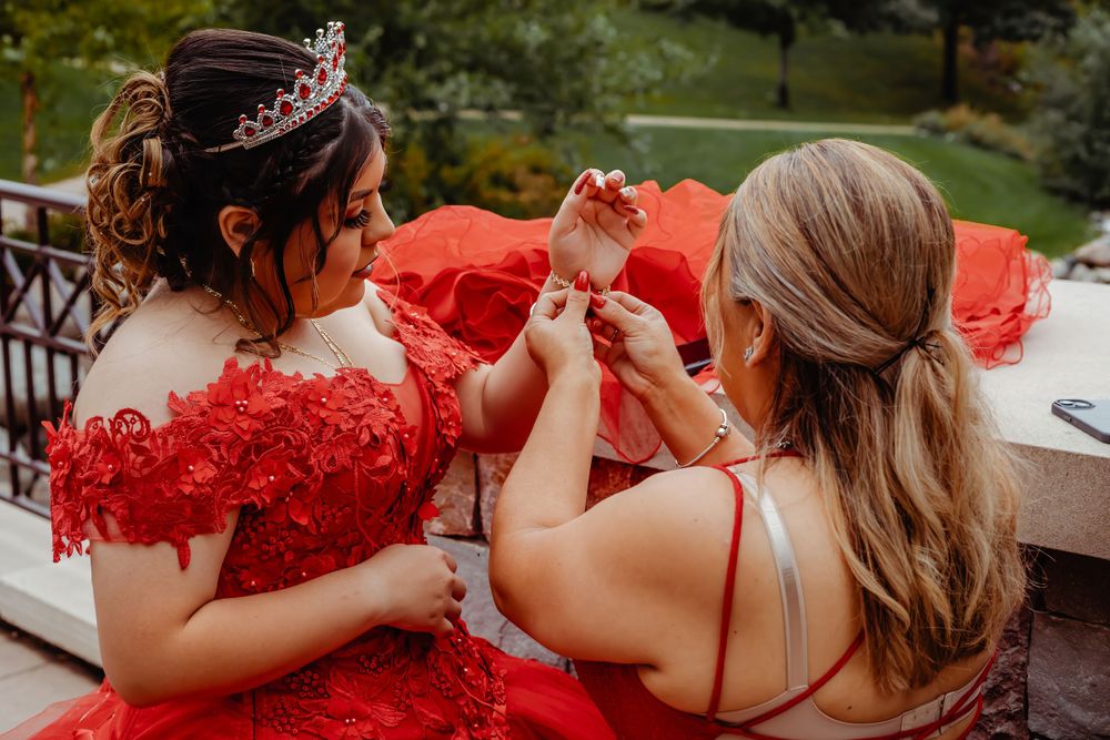 Someone in a red gown getting final adjustments made to their dress before an event.