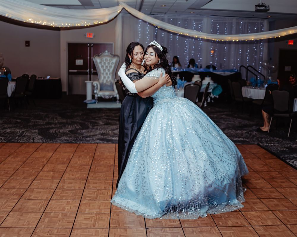 Celebratory dance scene in a decorated ballroom featuring a light blue ball gown.