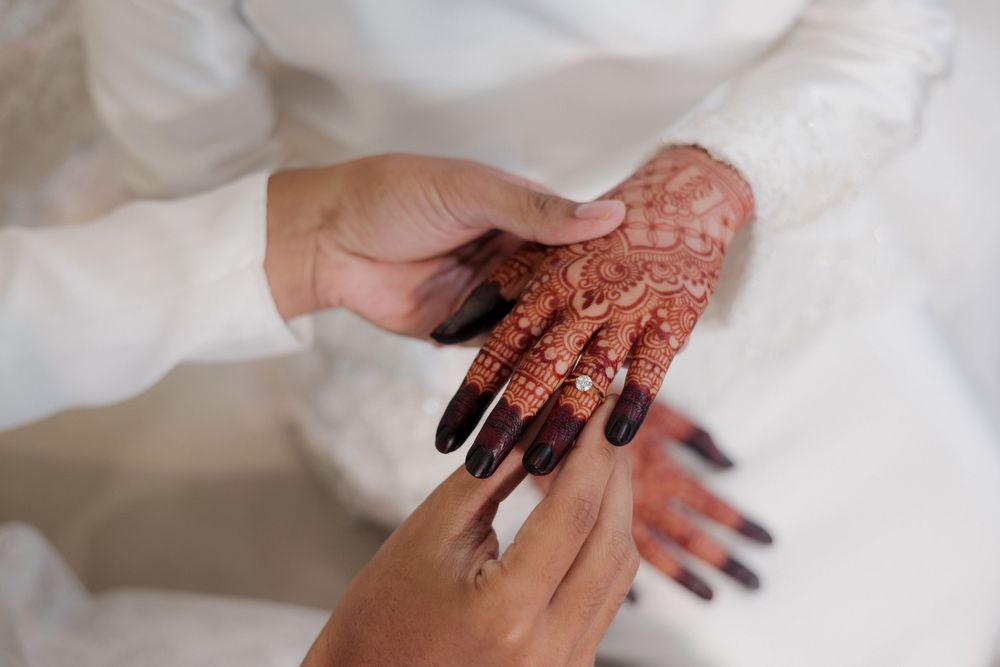 Close-up of intricate henna mehndi design on bride's hand being admired during traditional wedding ceremony.
