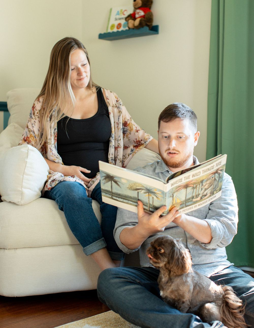 Hannah and David reading in their nursery during their in-home maternity session in Flint, Michigan